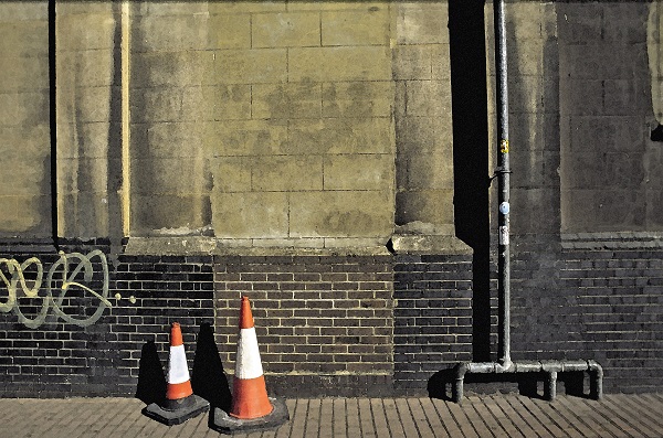 vodoravna fotografija dela stavbe v Londonu, z zunanjimi cevmi in dvema cestnima stožcema različnih velikosti
