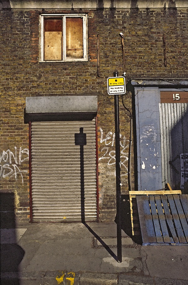 fotografija stavbe v Londonu s spuščenimi roloji na vratih in hišno številko petnajst, padajoča senca znaka na pločniku