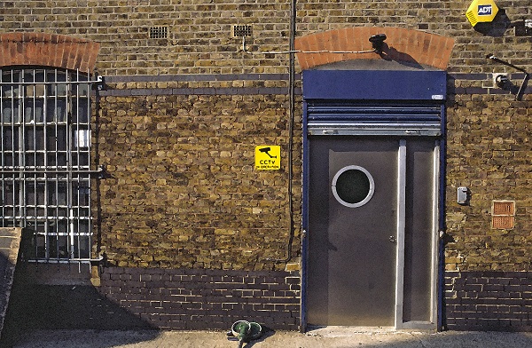 fotografija dela stavbe v Londonu, s sivimi vratii z okroglim oknom