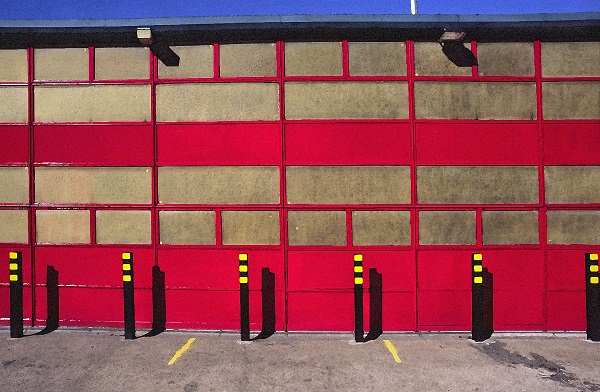 fotografija dela gasilske postaje v Londonu, rdeče in oker barve, s črno rumenimi količki pred objektom